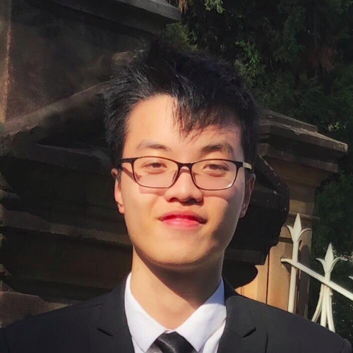 Professional headshot of Duy Long Nguyen wearing glasses and a light blue collared shirt, smiling against a neutral background.